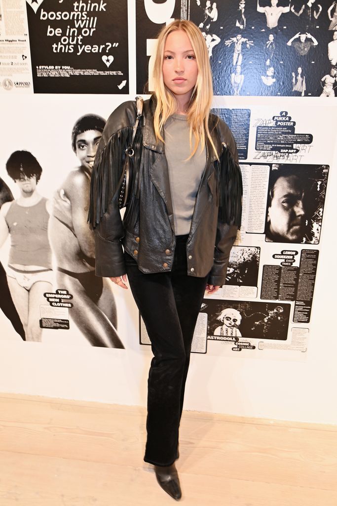 Lila Moss standing wearing a fringed leather jacket