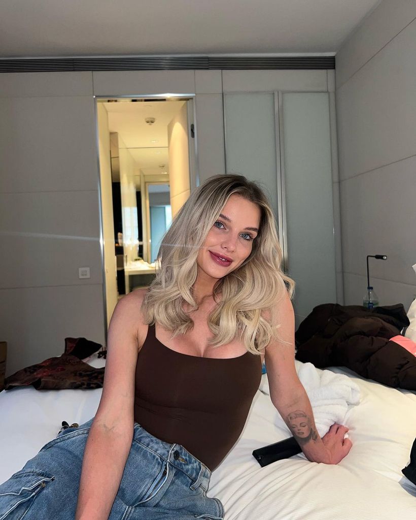 Helen Flanagan posing on hotel bed in black vest top and jeans