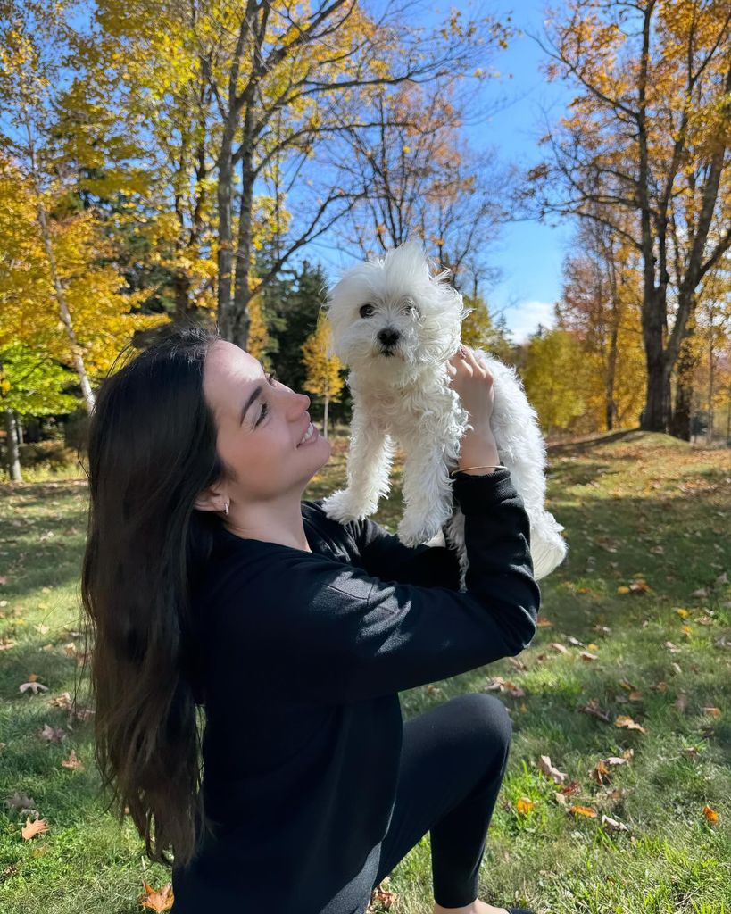 ana outside holding up white dog