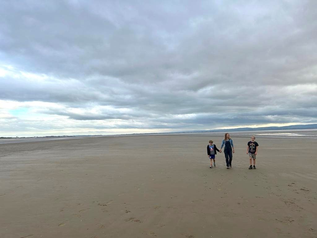 three people walking on the beach