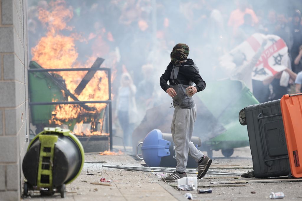 A young rioter surrounded by fires and overturned bins