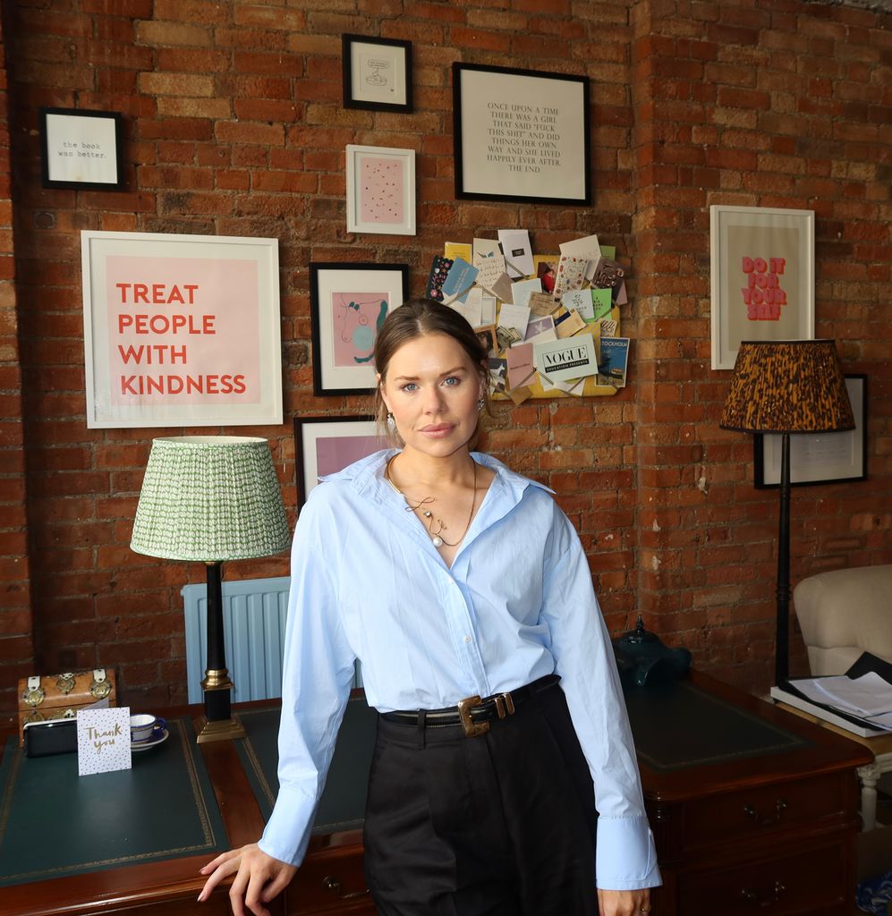 Woman in front of her desk in a blue shirt 