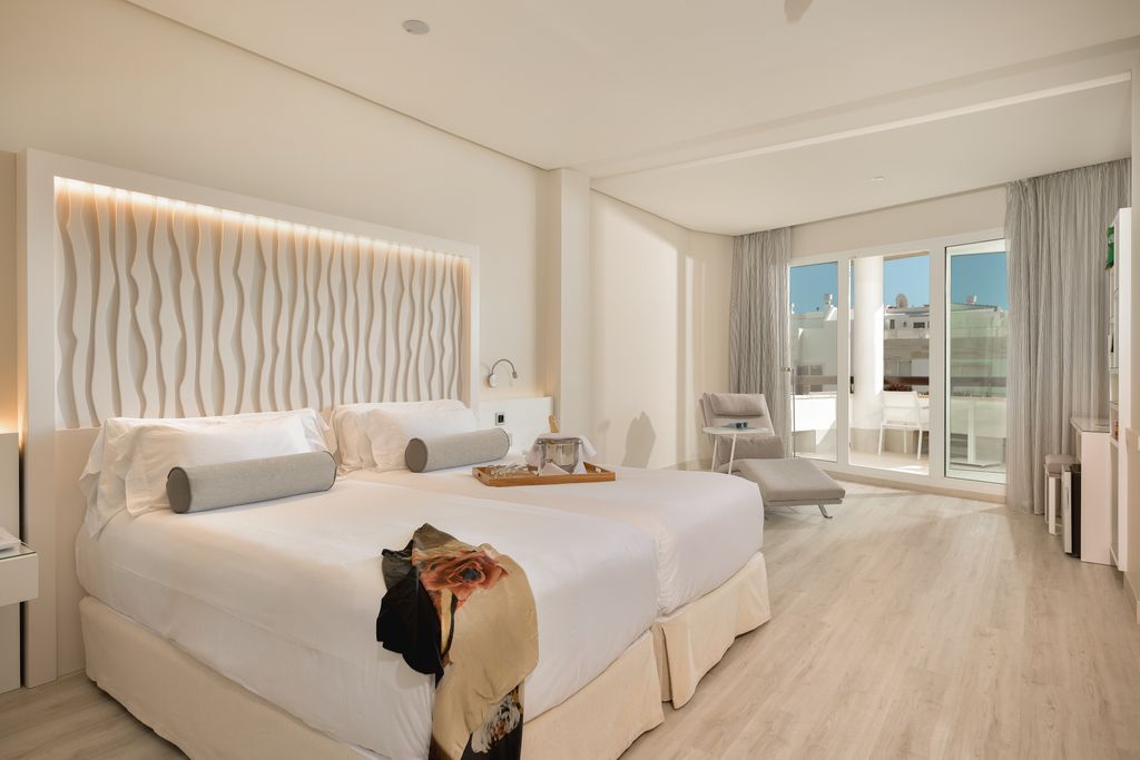 A stylish hotel bedroom in shades of cream with an outside balcony
