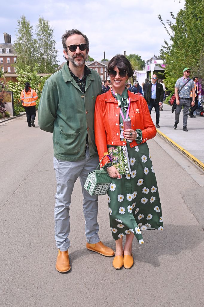 Chris O'Dowd and Dawn O'Porter attend Chelsea Flower Show wearing coordinated green and orange outfits with daisy prints and matching tan footwear.