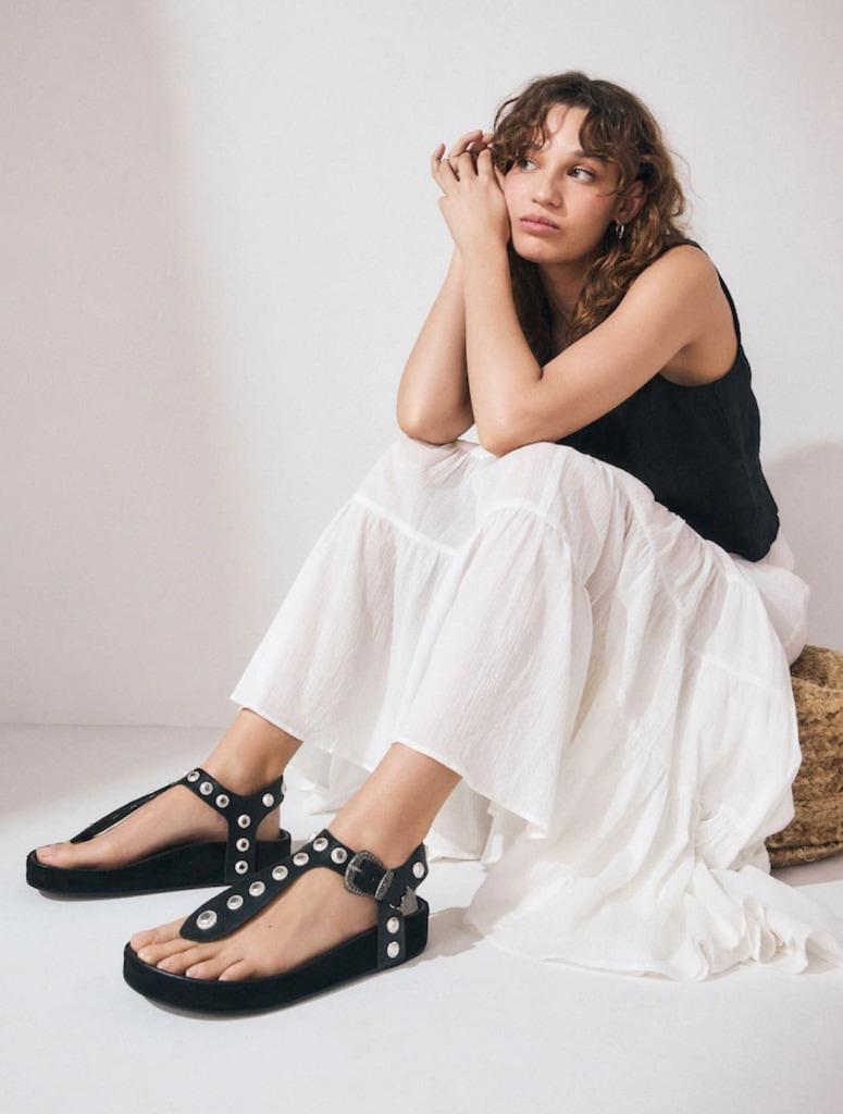 A model poses in a white skirt and black sandals for Next