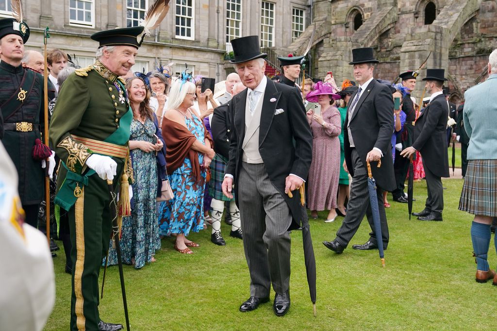 King Charles in top hat and holding umbrella