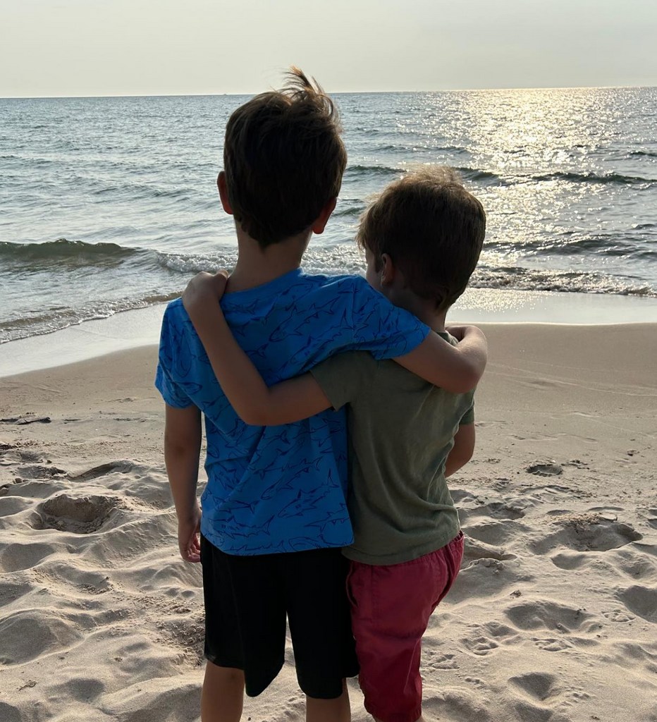 Photo shared by Ginger Zee on Instagram August 2023 of her sons Adrian and Miles in an embrace, looking at the distance from Michigan's Silver Lake