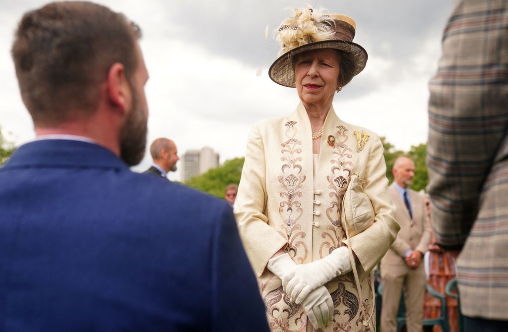 Princes Anne in an embroidered jacket talking to garden party attendees