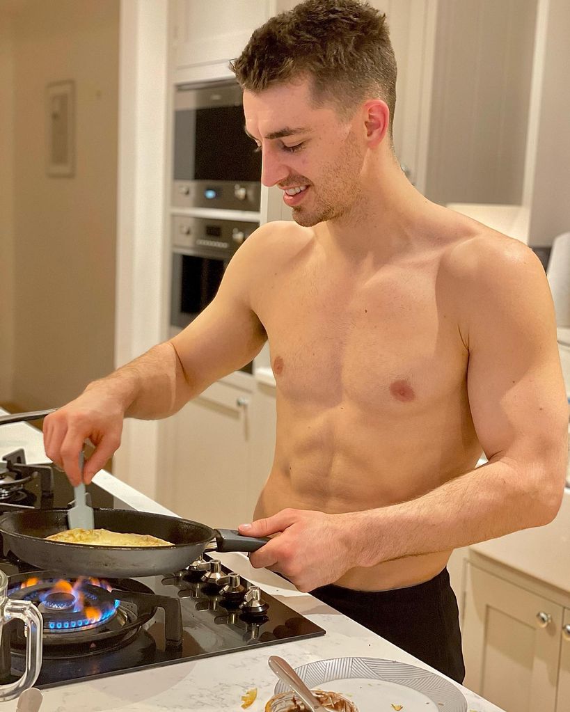 man cooking shirtless in kitchen