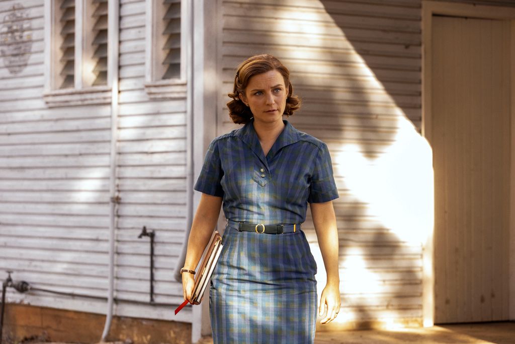 Woman in blue dress in front of house