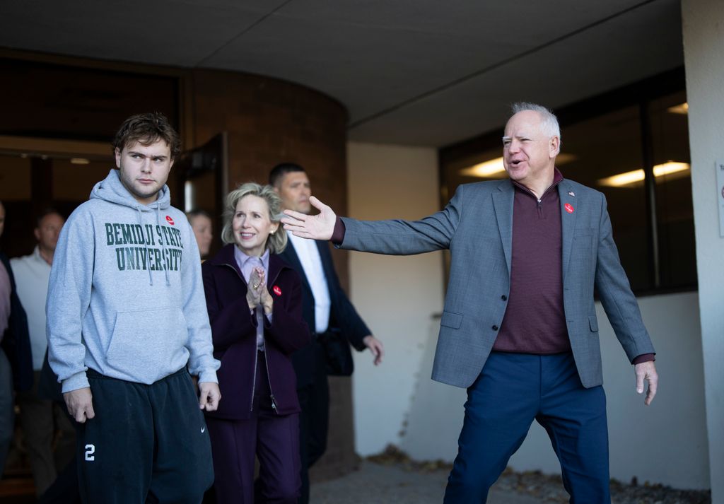 Minnesota Gov. Tim Walz, right, points to and announces his son Gus Walz was a first -time voter as they leave Ramsey County Elections after early voting in St. Paul, Minn., on Wednesday, Oct. 23, 2024