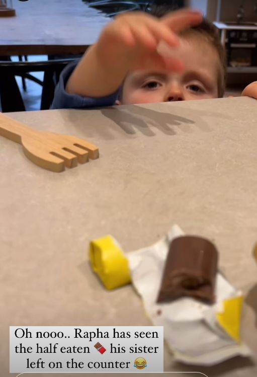 A young child reaching over a counter for a chocolate bar