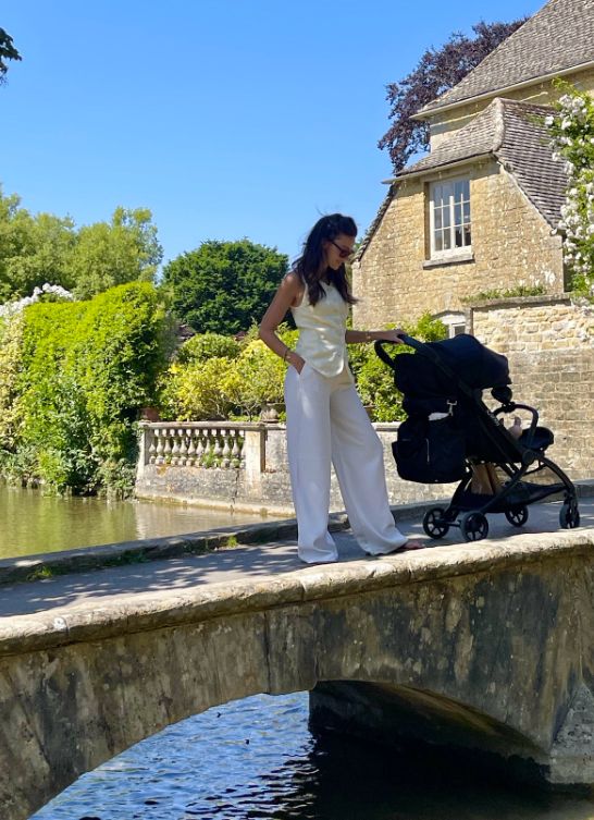 Michelle Keegan pushing a buggy on a small stone bridge