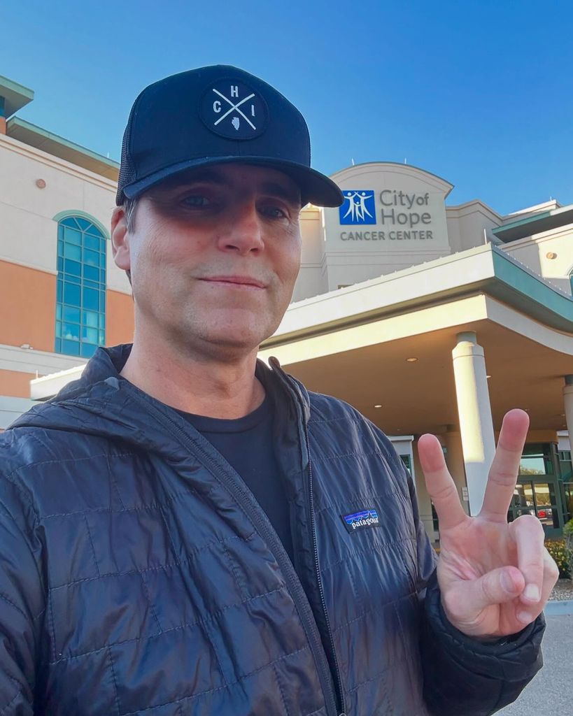 colin egglesfield holding up peace sign outside hospital