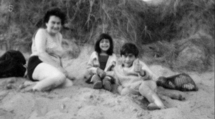A black-and-white photo of a mother with her son and daughter on the beach