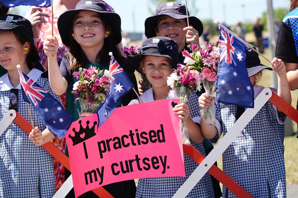 A schoolgirl holds up a sign as they await the arrival King Charles III and Queen Camilla arrive 