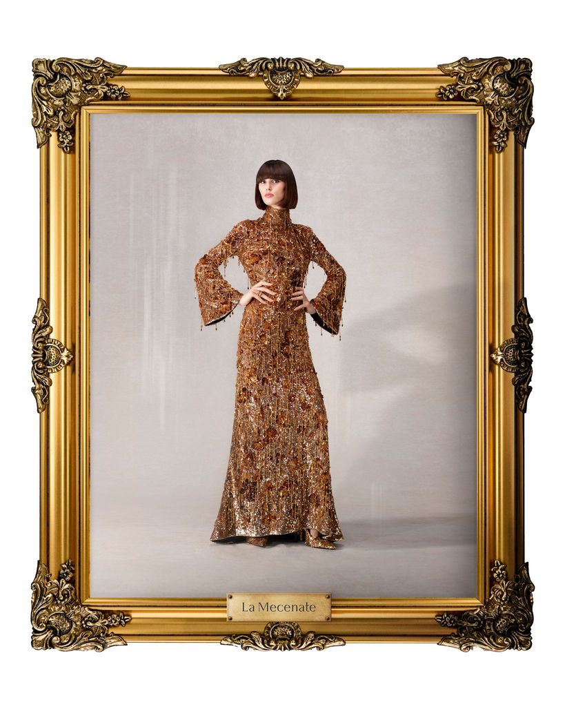 A model poses for a portrait in a bronze beaded gown with bell sleeves, covered with metallic embellishment. 