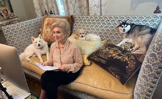 sharon osbourne sitting on sofa at home with her dogs