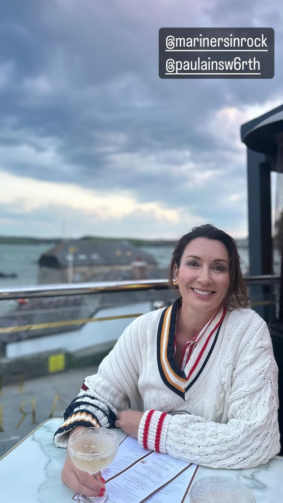 woman sat outside at table with glass 