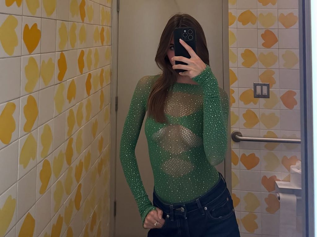 Alex Lee-Aillon in green sheer bodysuit and jeans