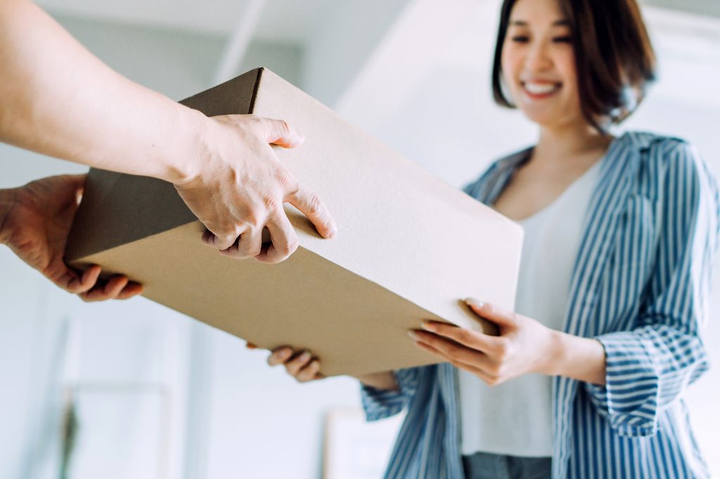 Close up of a courier person making a delivery to a customer at home. Providing a swift express delivery straight into customer's hands