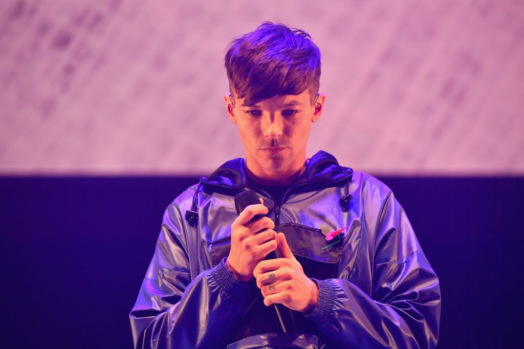 Louis Tomlinson holding a microphone