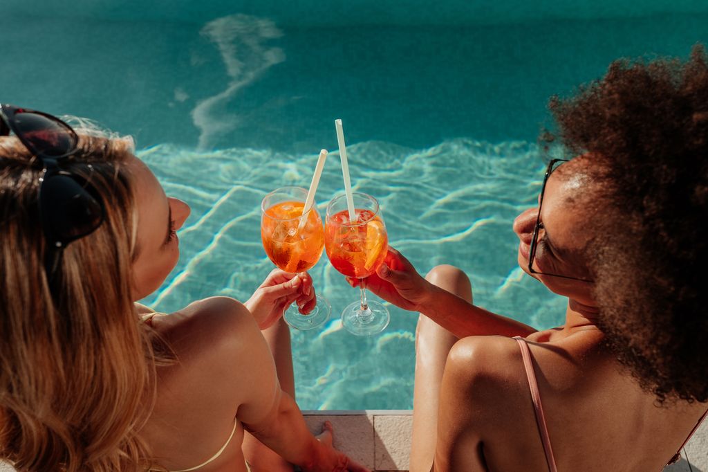 Female friends at a poolside summer party enjoying cocktails