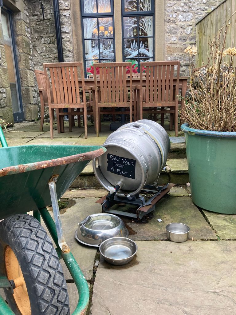 Barrel of water and dog bowls in a pub courtyard 