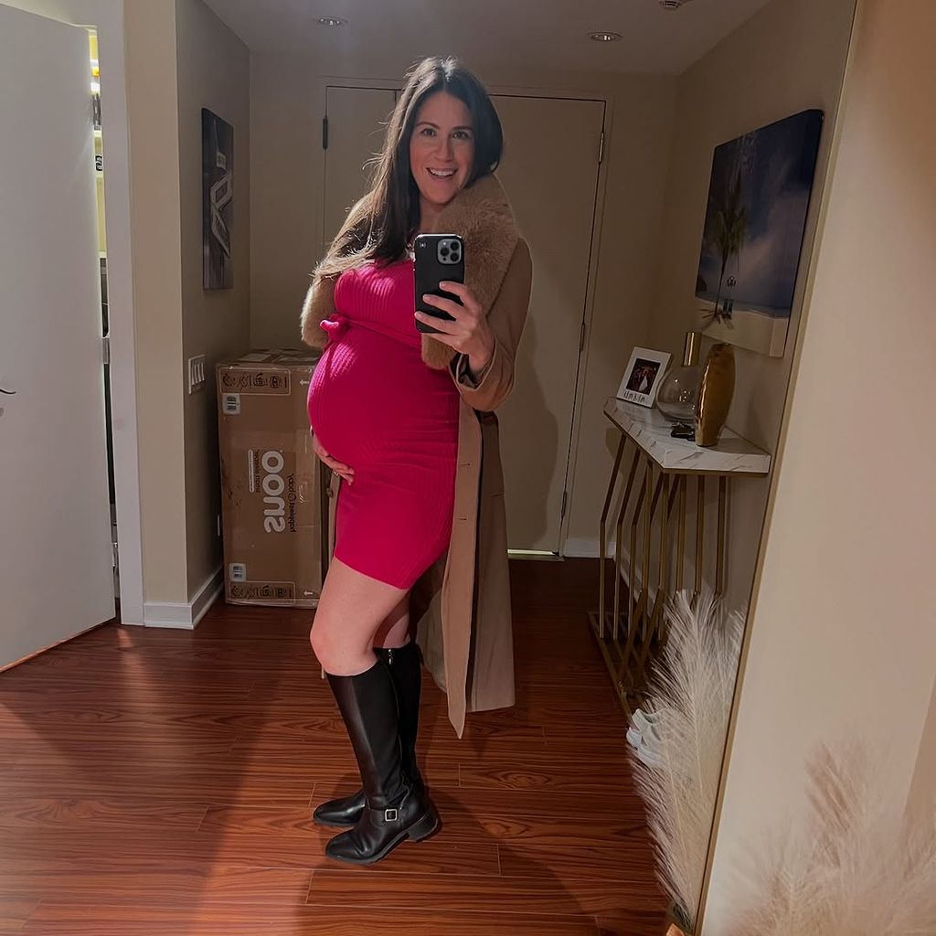 Stephanie Mansour cradles her baby bump in a selfie at home, shared on Instagram