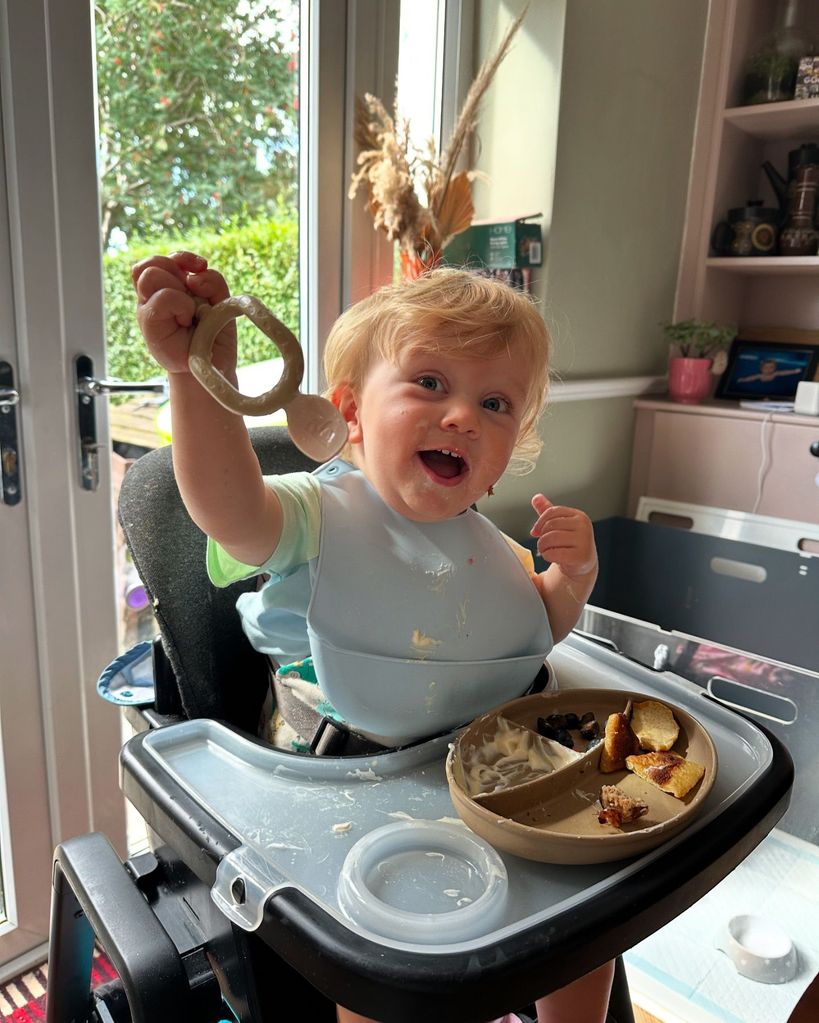 little boy sat eating meal in highchair