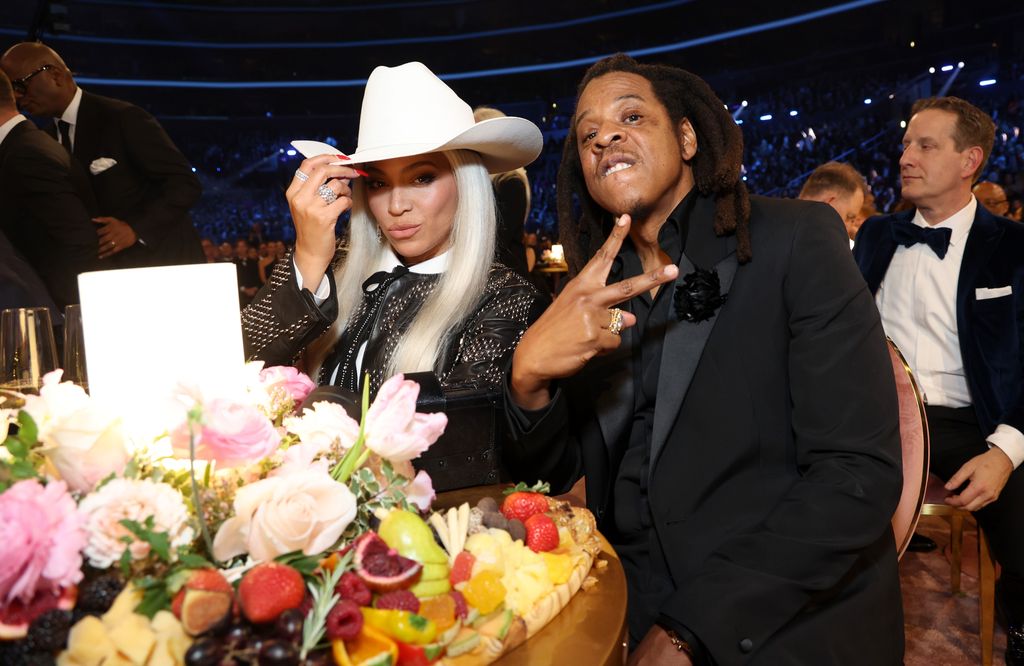 Beyonce wearing white cowboy hat posing with husband Jay Z at table at GRAMMYs 2024