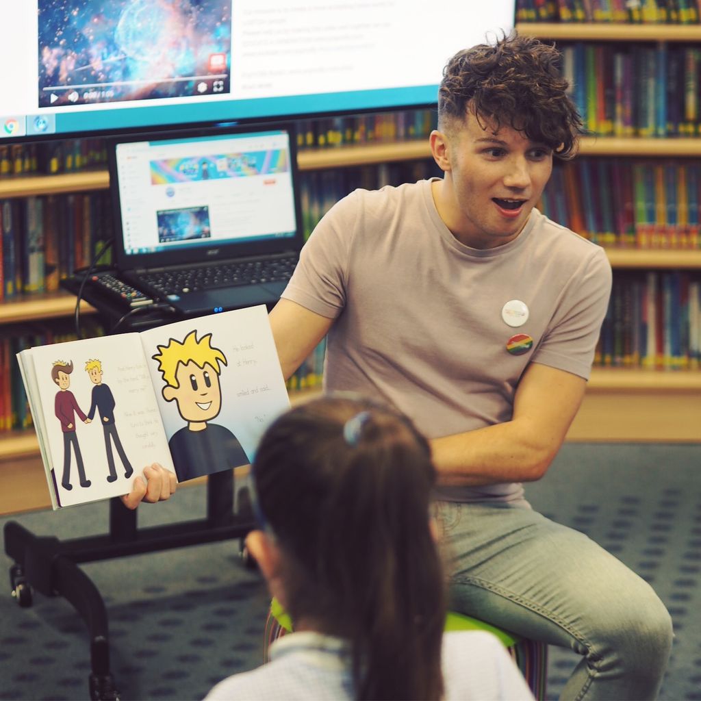 Olly Pike reading a book to a group of children