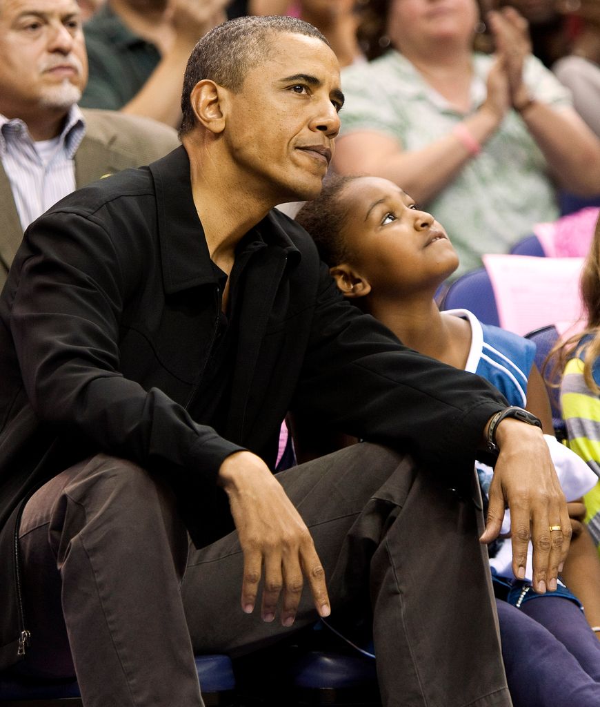 President Barack Obama and his daughter Sasha watch a basketball game