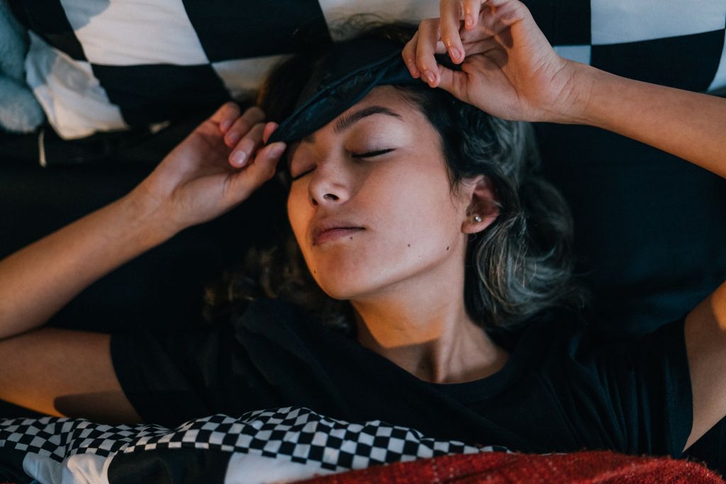 Woman waking up in bed with sleep mask on