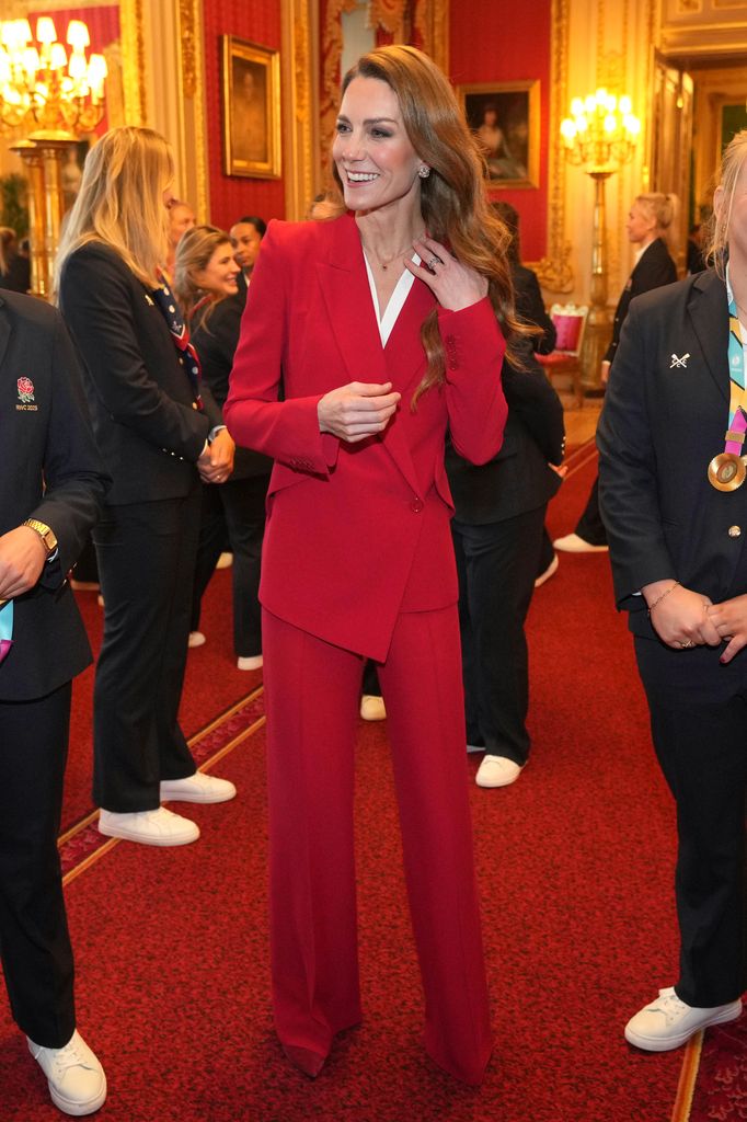 Kate Middleton souriante en costume rouge