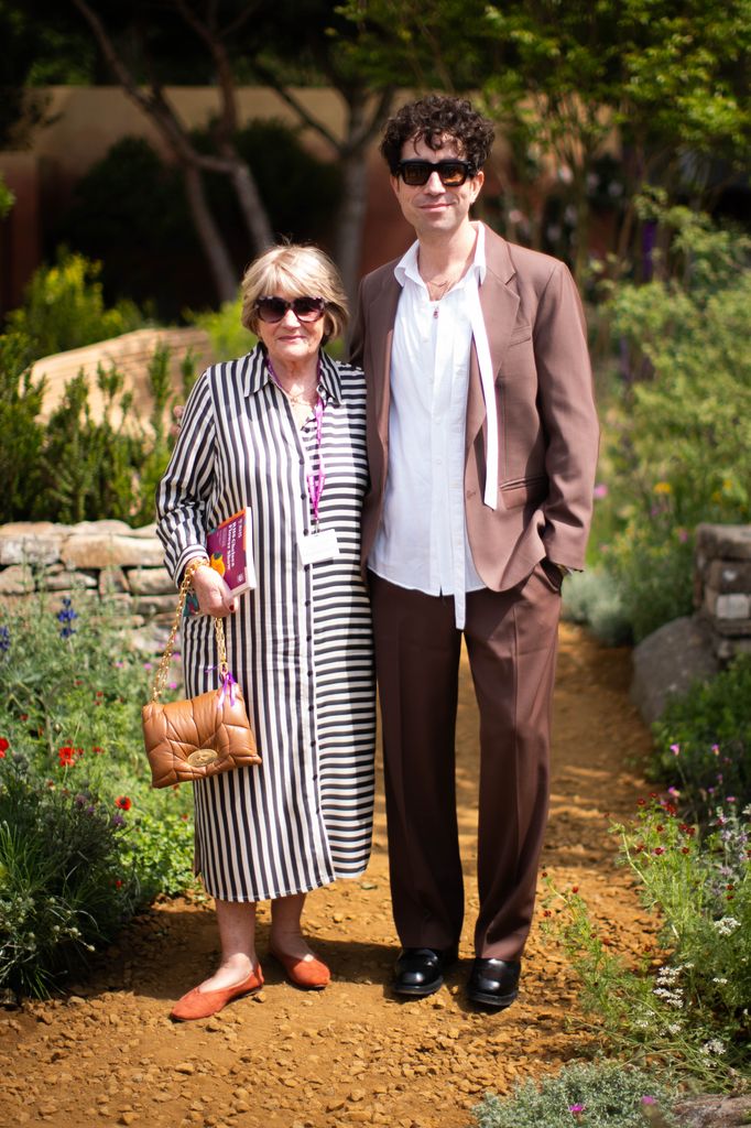 Eileen Grimshaw in a striped shirtdress and Nick Grimshaw in a brown suit and white shirt smile at Chelsea Flower Show.