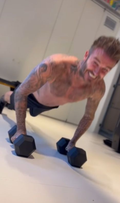 David Beckham shirtless in black shorts doing weighted press-ups