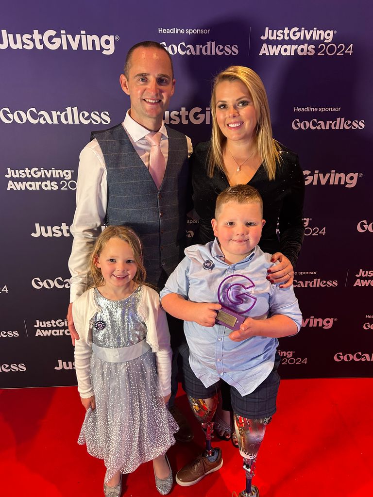 young boy holding trophy alongside family