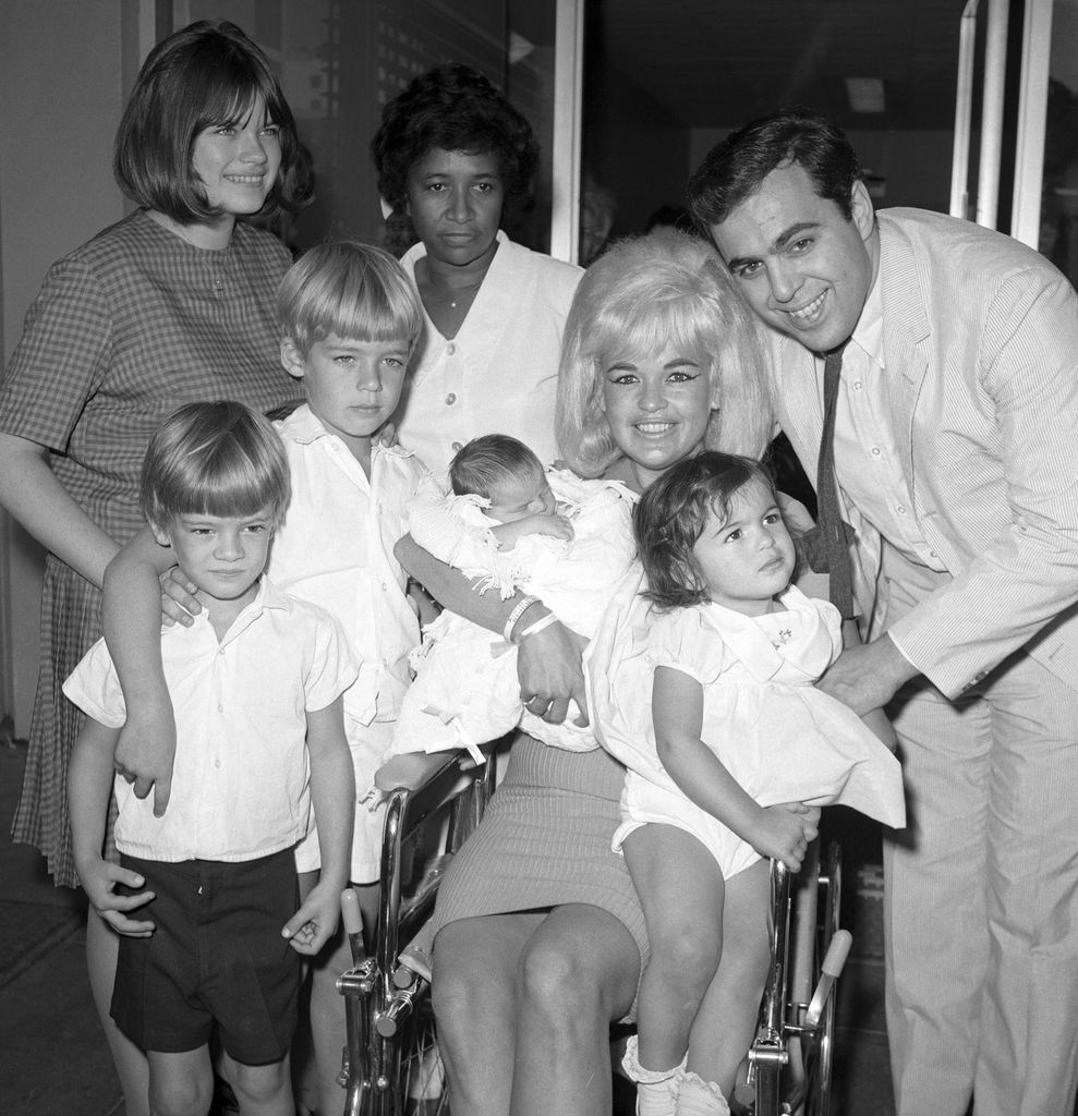 Actress Jayne Mansfield and family are pictured here as the blonde actress leaves Cedars of Lebanon Hospital with the newest addition to the family, baby Anthony. Left to right are Jayne Marie Mansfield, 15, Zoltan Hargitay, 5, Mickey Hargitay Jr., 6, unidentified hospital attendant, Jayne holding baby Anthony, and husband Matt Cimber with Mariska Hargitay, 1. Anthony is the first child by Cimber.