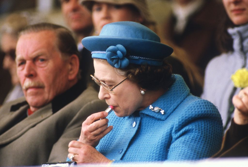 Queen Elizabeth II putting on lipstick