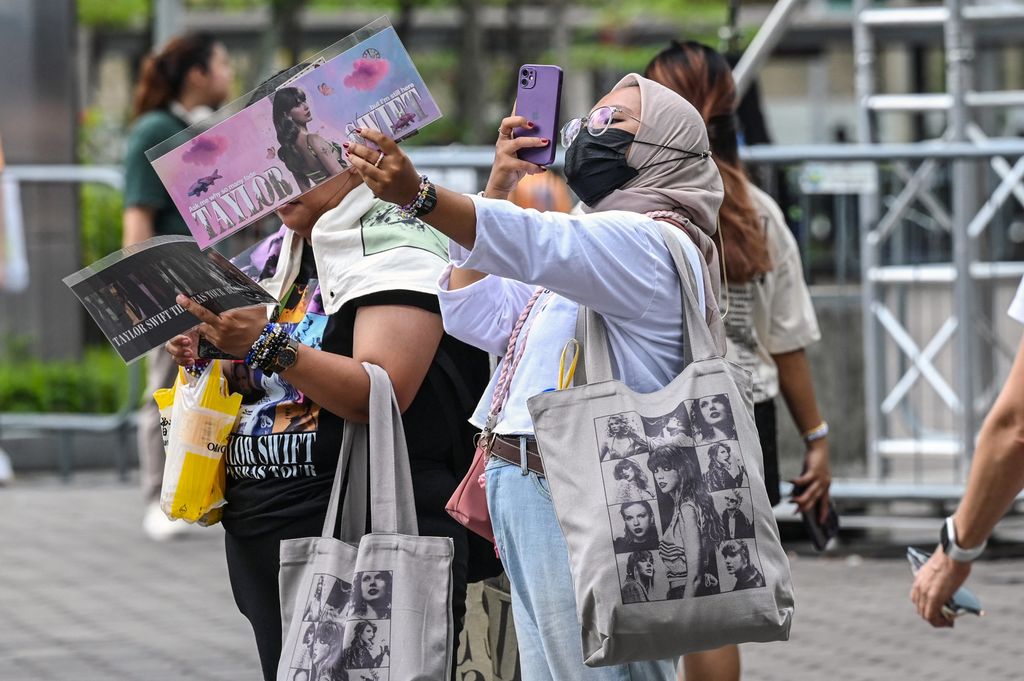 Taylor Swift fans pose with her merchandise