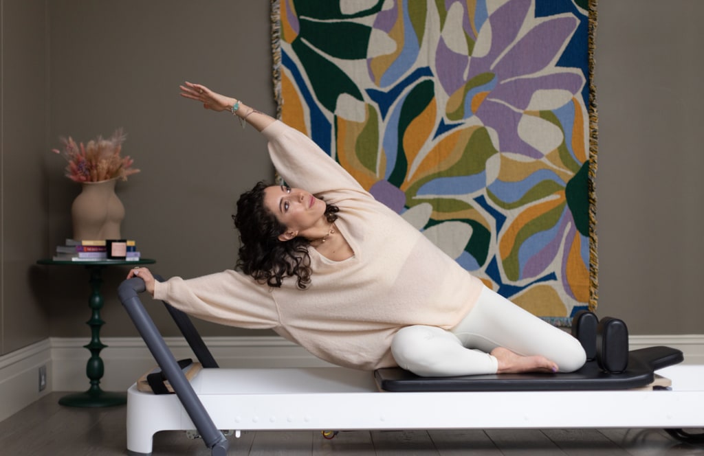 Woman in exercise wear stretching on a reformer bed