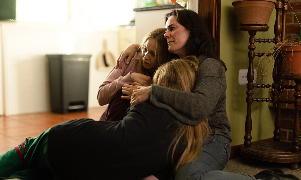 mother hugging daughters sitting on floor