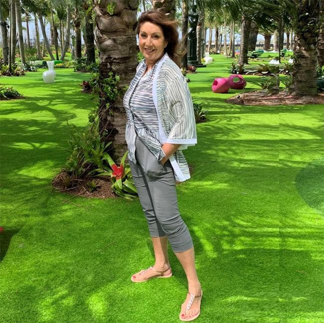 Jane McDonald standing with palm trees