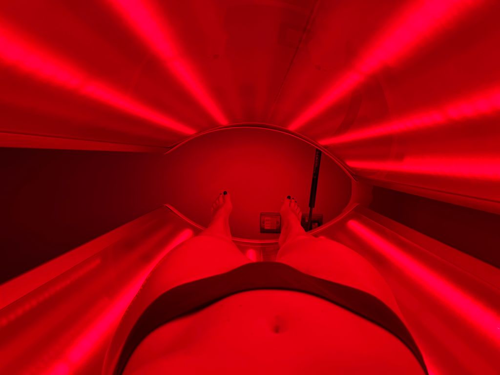 Legs inside a red light therapy chamber
