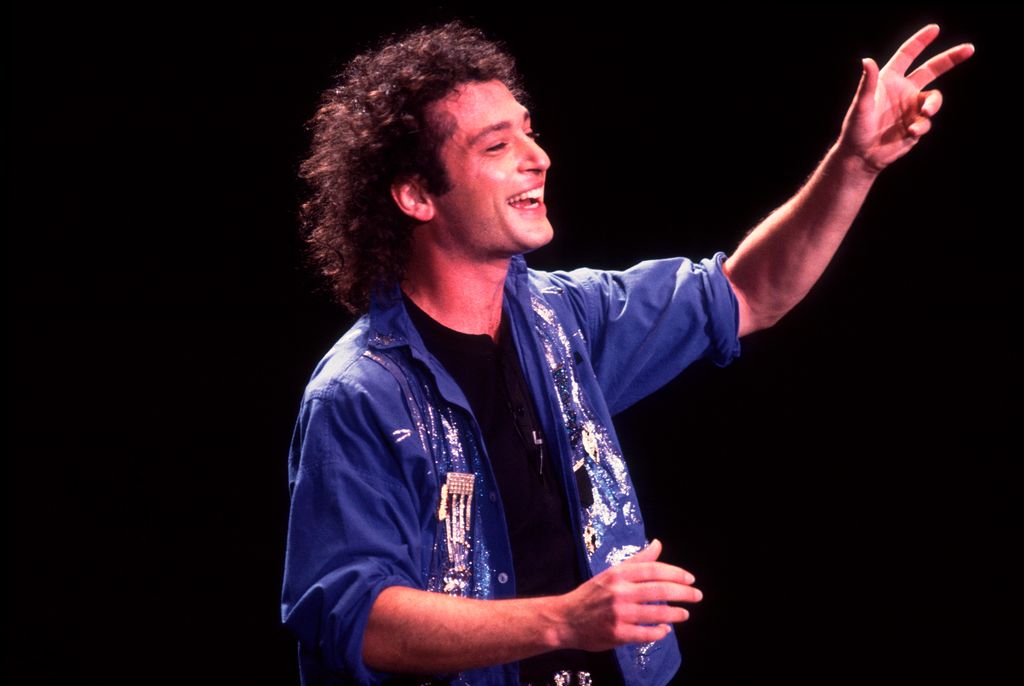 photo of howie mandel with long curl hair on stage in 1985