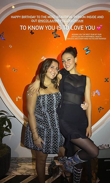 Nicola Peltz Wearing A Black Sheer Dress With An Arm Around Her Friend 