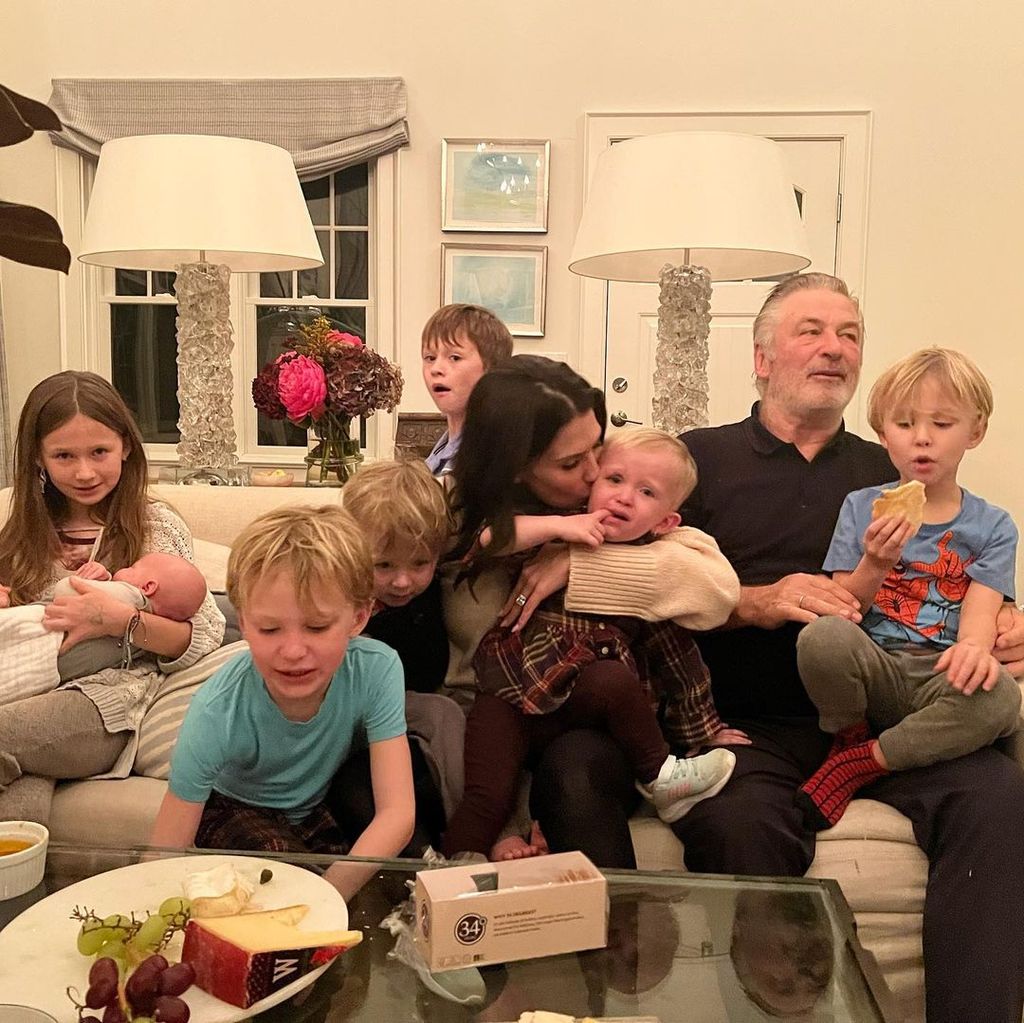 Alec and Hilaria Baldwin in living room with seven children