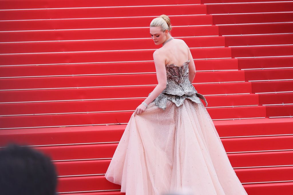 Elle Fanning climbs the steps in her glamorous ballgown