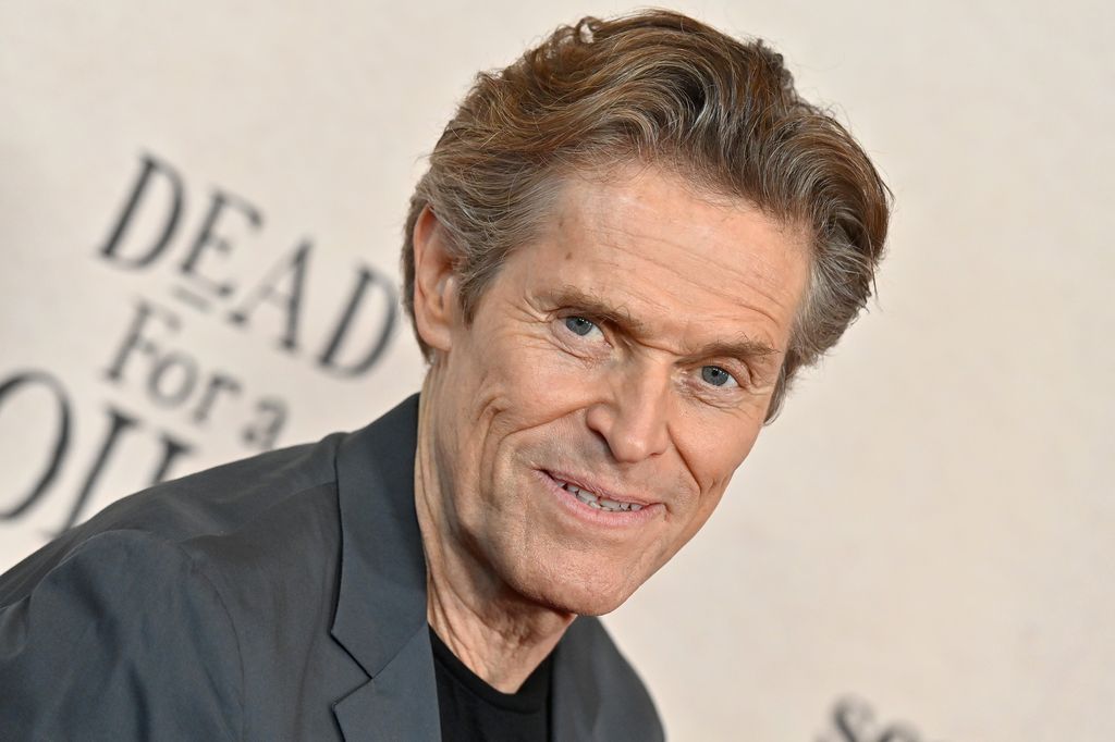 Willem Dafoe in grey suit jacket